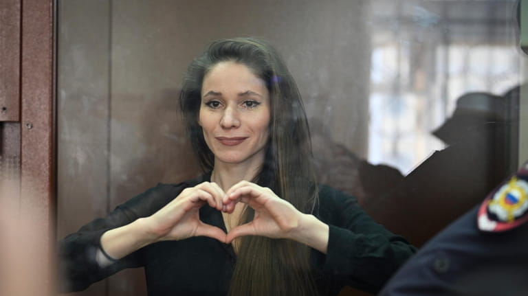 Antonina Favorskaya stands in a glass cage in a courtroom...