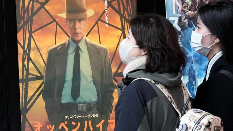 People walk by a poster to promote the movie "Oppenheimer"...