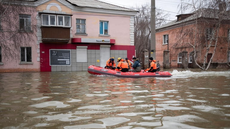 Emergency workers and police ride a boat during evacuations in...