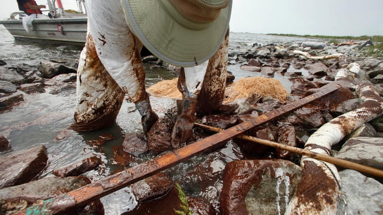 A cleanup worker picks up blobs of oil in absorbent...