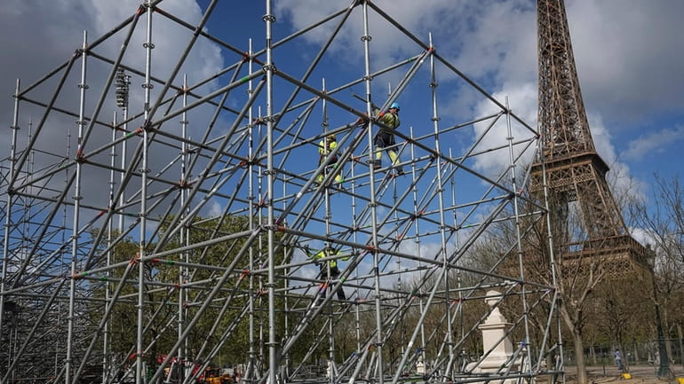 Workers build constructions on the Champ-de-Mars, near the Eiffel Tower,...