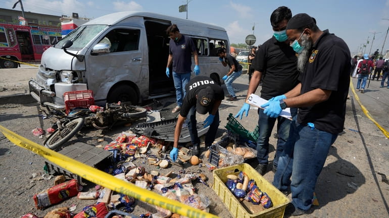 Investigators examine the site of a suicide attack in Karachi,...