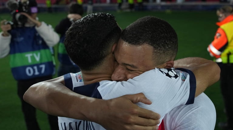 PSG's Kylian Mbappe, right, celebrates with his teammate Achraf Hakimi...