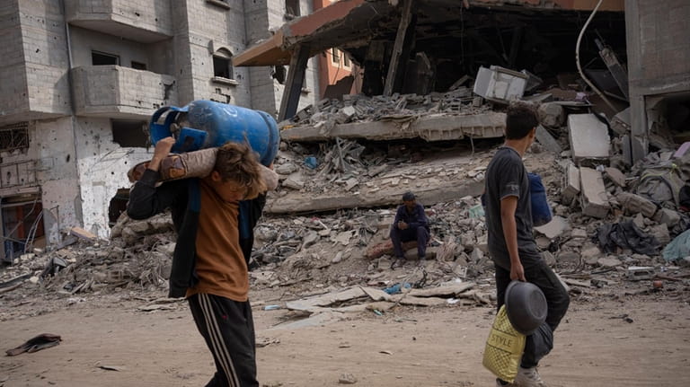 Palestinians walk through the destruction in the wake of an...