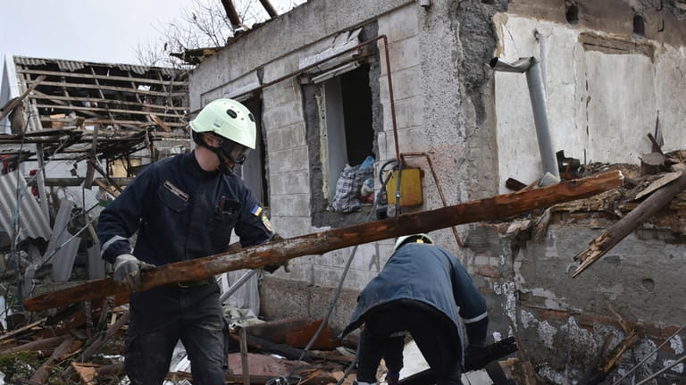 Rescue workers clear the rubble of a destroyed house after...