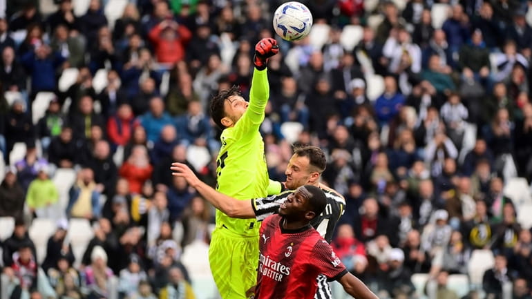 AC Milan's goalkeeper Marco Sportiello, left, punches away the ball...