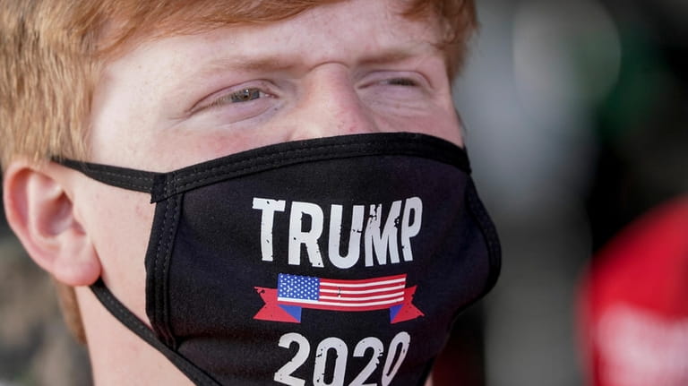 A supporter wears a "Trump 2020" face mask before a...