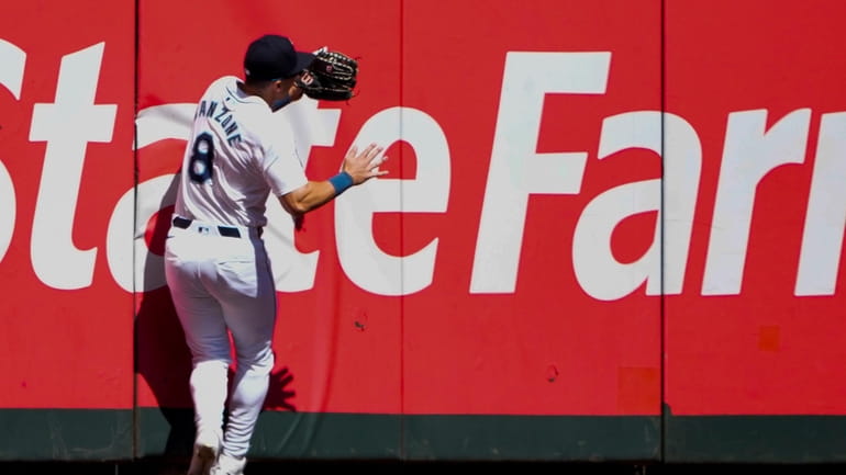 Seattle Mariners left fielder Dominic Canzone collides with the wall...