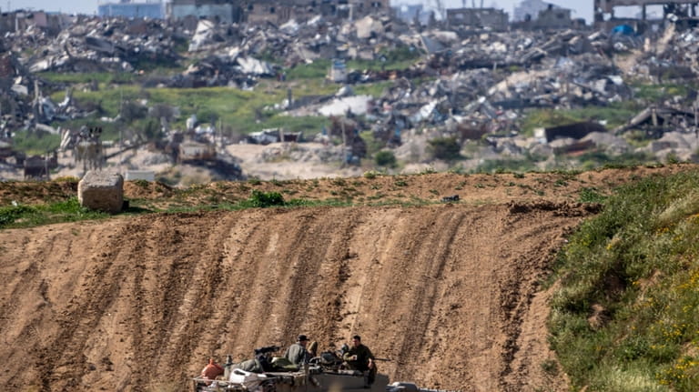 Israeli soldiers rest on top of their tank on the...