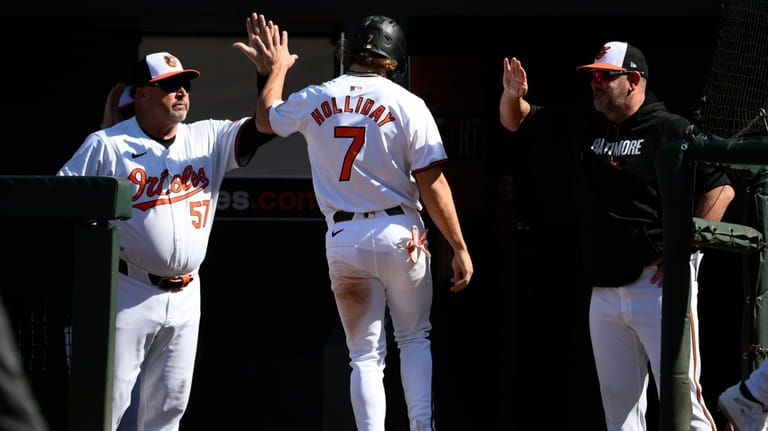 Baltimore Orioles' Jackson Holliday (7) is greeted by bench coach...