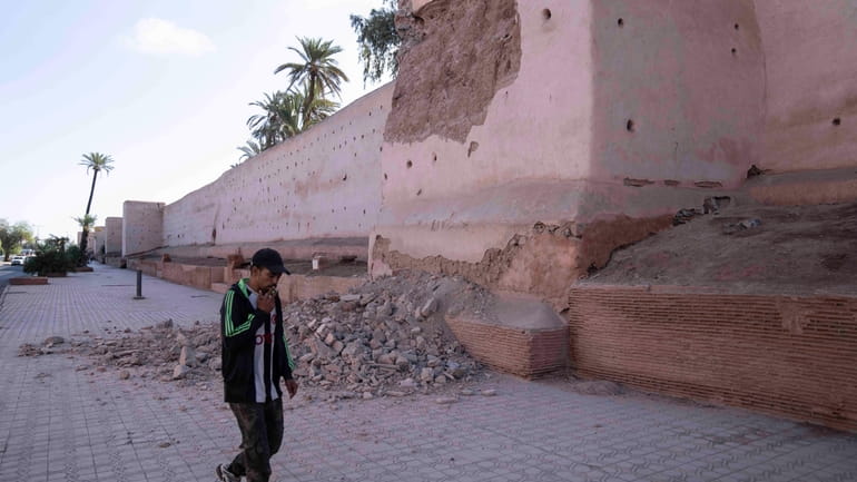 A man walks past a damaged wall of the historic...