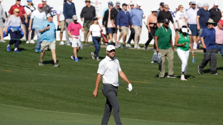 Scottie Scheffler, front, walks with the gallery to the 18th...