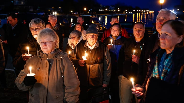 Community members hold a candlelight vigil in support of those accusing...