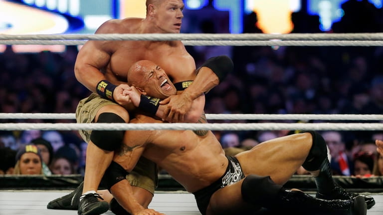 Wrestler John Cena, top, chokes Dwayne "The Rock" Johnson at...