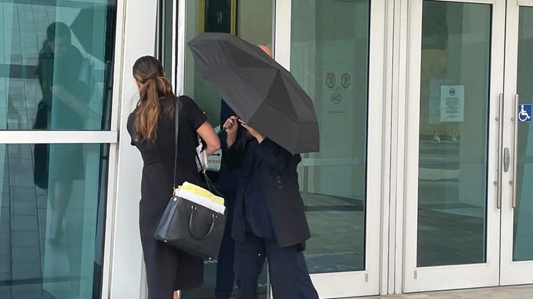 Celebrity handbag designer Nancy Gonzalez hides under an umbrella as...