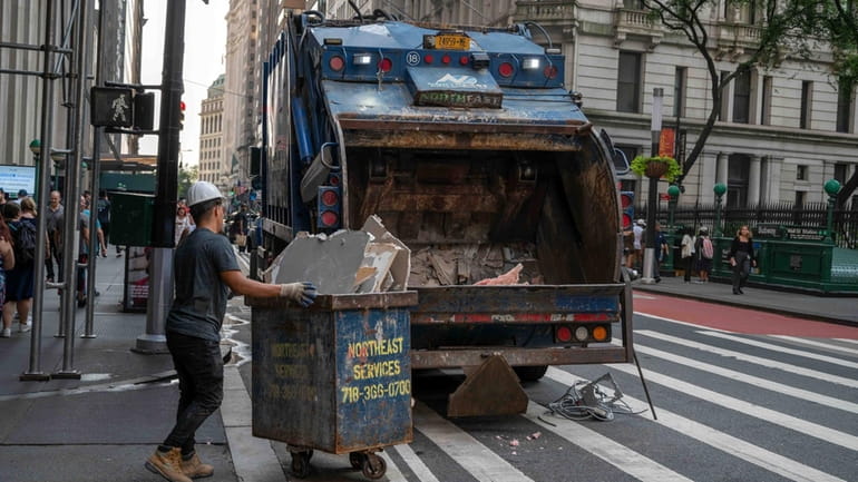 New York, NY, USA, 07-18-2023 Sanitation workers roll trash bins...