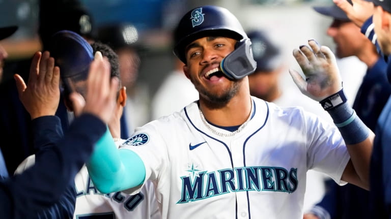 Seattle Mariners' Julio Rodríguez celebrates in the dugout after scoring...
