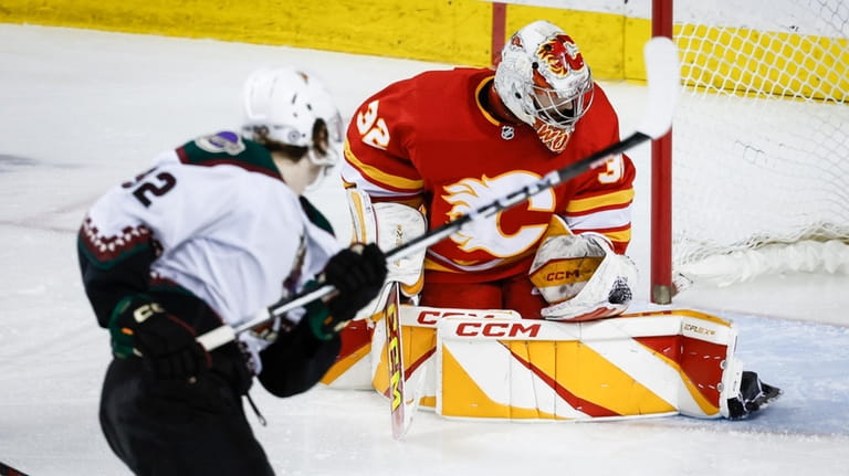 Calgary Flames goalie Dustin Wolf (32) stops a shot by...