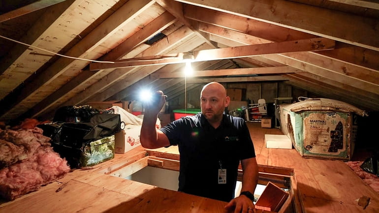 Jamie Culbertson of Green Team LI inspects the attic during a free energy...