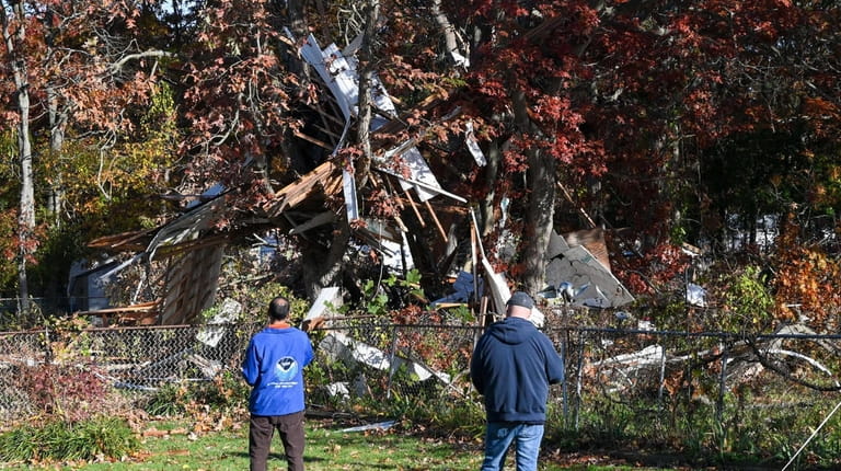 National Weather service meterologist Nelson Vaz surveys damage in backyard of...