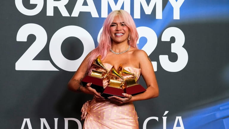 Karol G poses with the awards for best urban album...