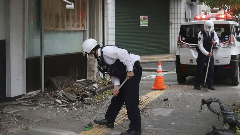 Police officers clean the debris from an earthquake in Uwajima,...