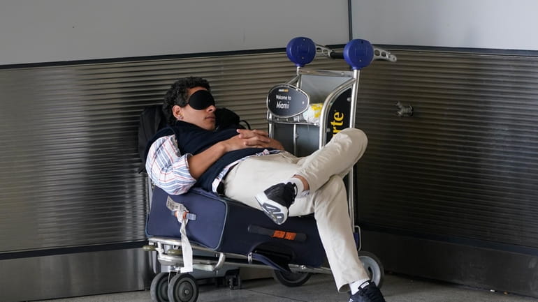 A traveler takes a nap as he waits for a...