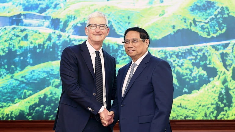 Apple CEO Tim Cook, left, shakes hands with Vietnamese Prime...