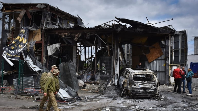 Ukrainian servicemen pass the scene of a building damaged by...