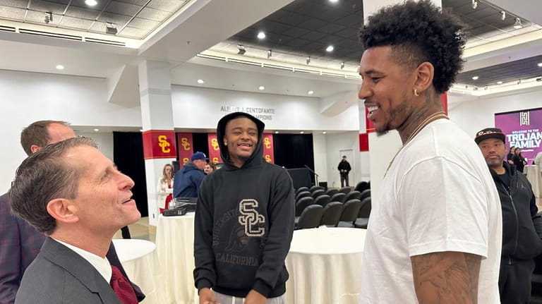 Eric Musselman, left, talks with current player Isaiah Collier, center...