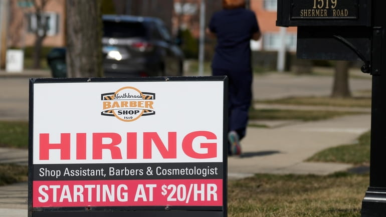 A hiring sign is seen outside of a barber shop...