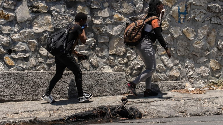 EDS NOTE: GRAPHIC CONTENT - Pedestrians walk past a charred...