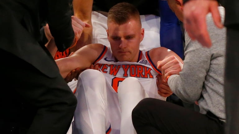 Kristaps Porzingis of the New York Knicks is helped off...