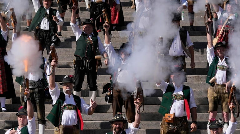 Bavarian riflemen and women in traditional costumes fire their muzzle...