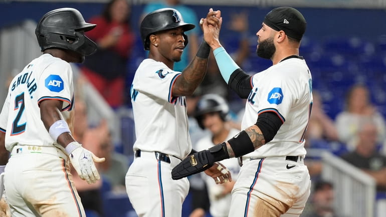Miami Marlins' Tim Anderson, left, and and Emmanuel Rivera score...