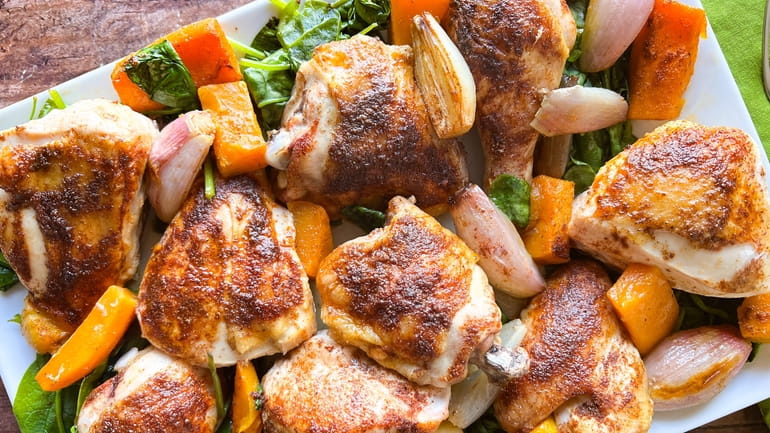 Spice-rubbed chicken is roasted with butternut squash and shallots on...