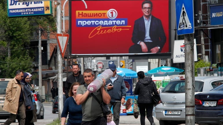 People walk past election poster of Stevo Pendarovski, incumbent President...