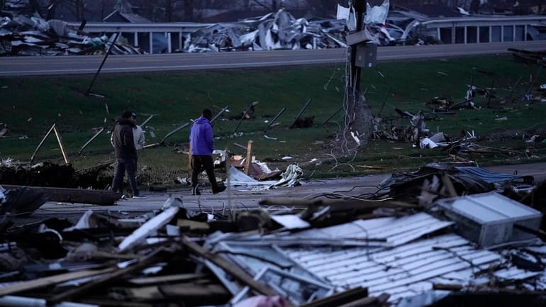 People walk through debris from severe storms Friday, March 15,...