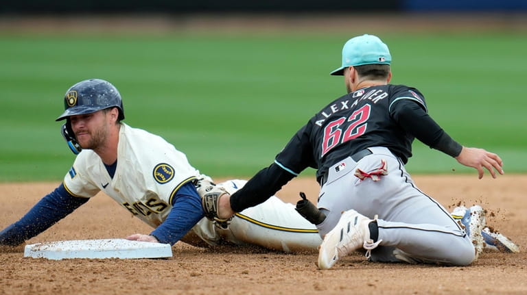 Milwaukee Brewers' Brice Turang, left, steals second base as Arizona...
