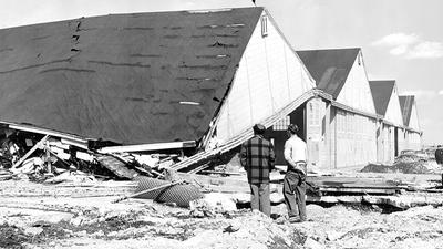 Two men observe demolition of hangars at Roosevelt Field on...