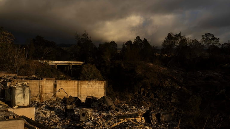 Clouds hang over a home destroyed in a wildfire in...