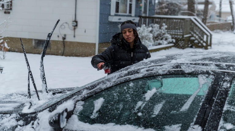 Aryanna Zito, 17, cleans snow off car in Shirley on...