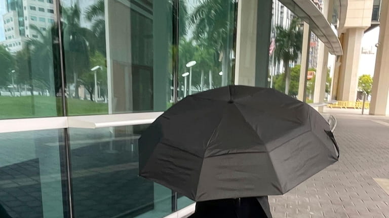 Celebrity handbag designer Nancy Gonzalez hides under an umbrella as...
