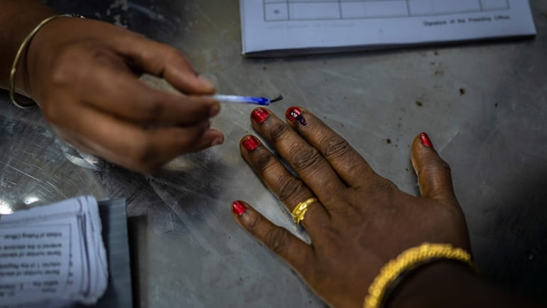 A polling official puts indelible ink mark on the index...