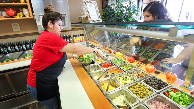 Employee Elba Perez works on a customer’s salad order at the...