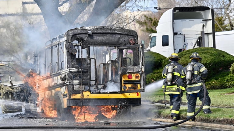 Firefighters work to extinguish a mini school bus fire on...