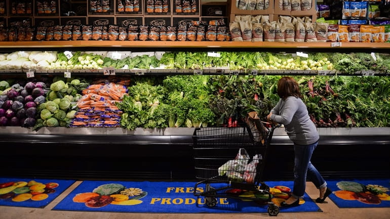 A woman browses the produce section of a grocery store...