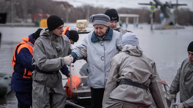 Emergency workers assist a woman to deboard a boat during...