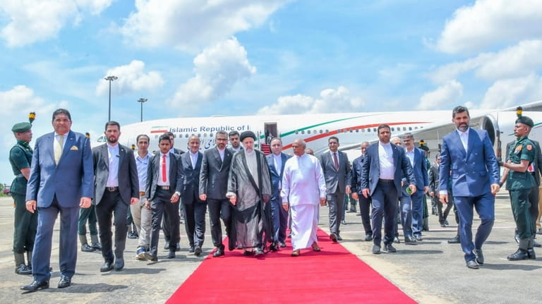 Iranian President Ebrahim Raisi, center left is received by Sri...