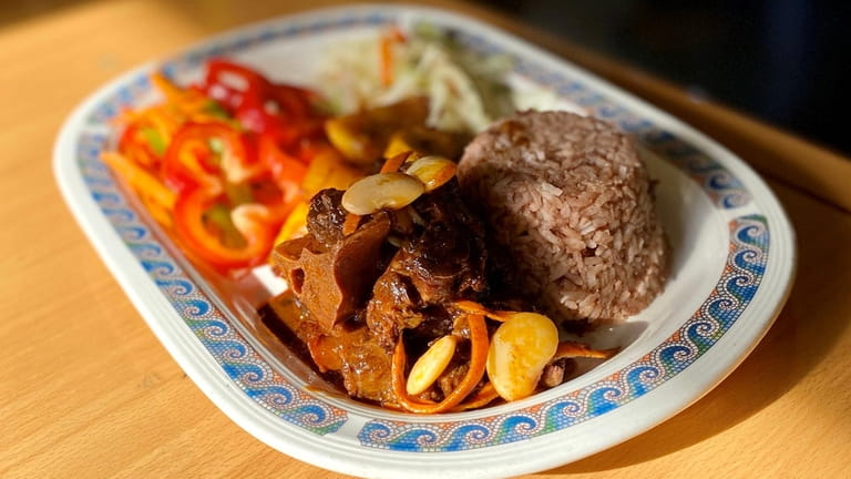 Oxtail is served with rice and peas, vegetables and cabbage...